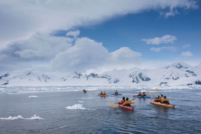 Kayakers paddle between sea ice