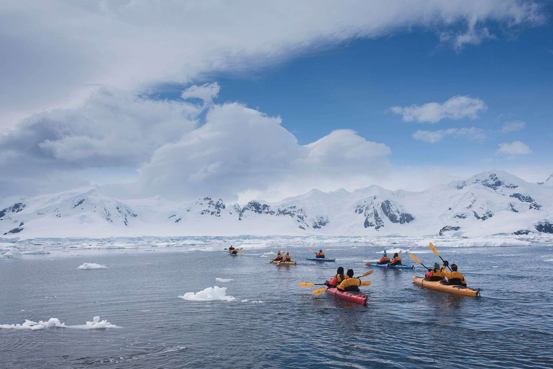 Kayakers paddle between sea ice